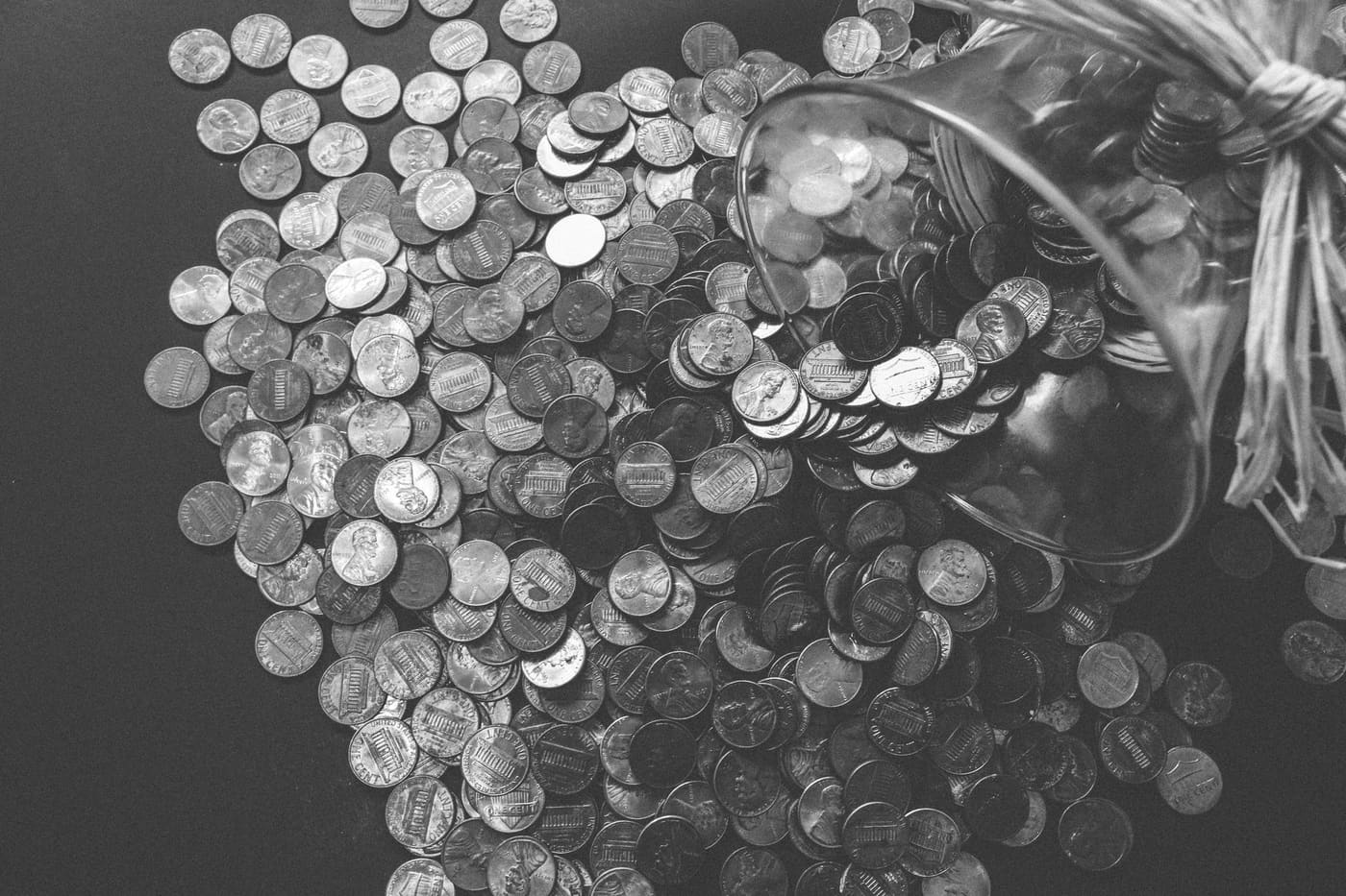 Black-and-white photo of coins spilling out of a glass jar